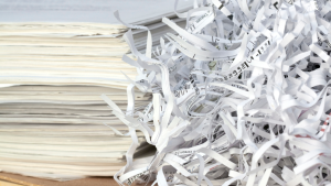 Shredded paper beside a stack of documents representing secure document shredding services.